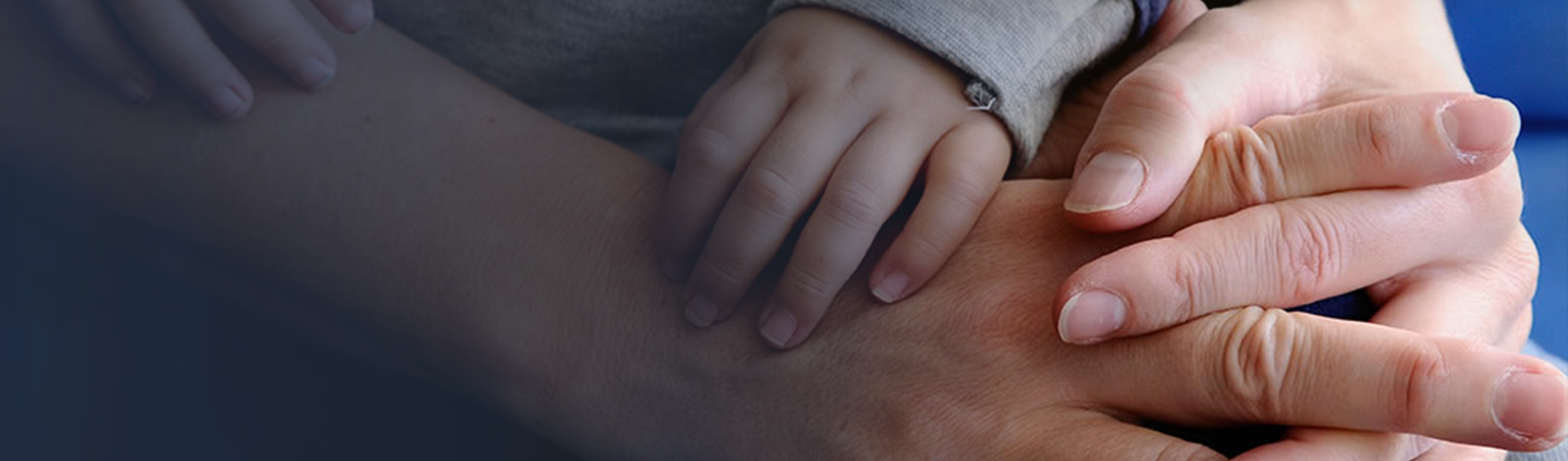 An RMHC family, close up on the hands of an infant holding onto the arm and wrist of one parent holding the hand of another