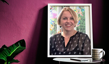 Framed portrait, Kelly Dolan, on desk with mug in purple digital background, plant leaf
