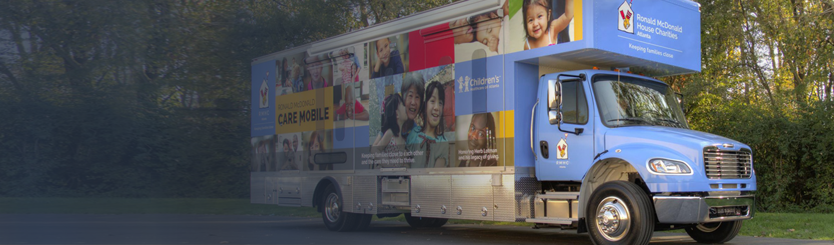 A parked Care Mobile against a background of trees, vehicle wrapped in RMHC family imagery and messaging, RMHC Atlanta