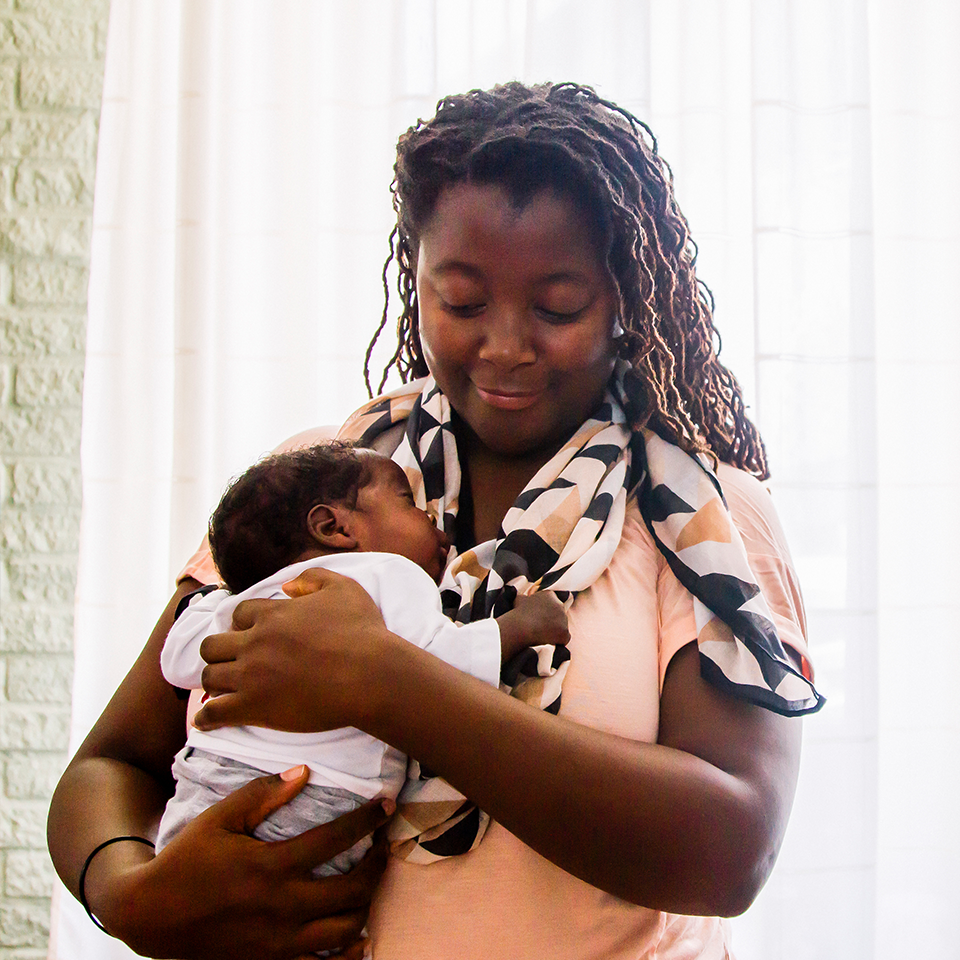 RMHC family, mom comforting her infant in a space near the site of care in a Family Room program space