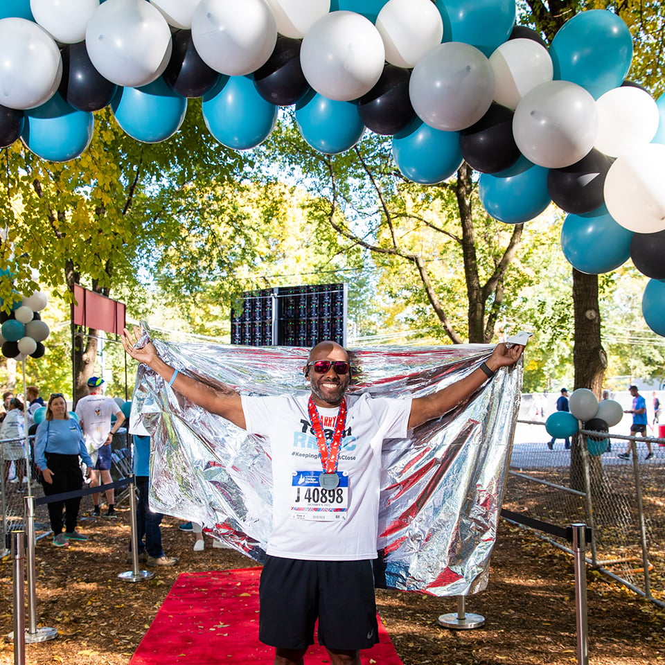 A Team RMHC marathoner after the finish line, space blanket, bib, and medal 960x960